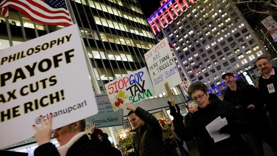 Manifestantes sostienen pancartas contra la reducción de impuestos para los ricos en Estados Unidos