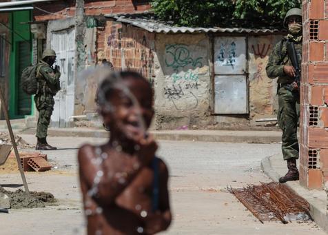 Un niño juega con agua en medio del operativo militar