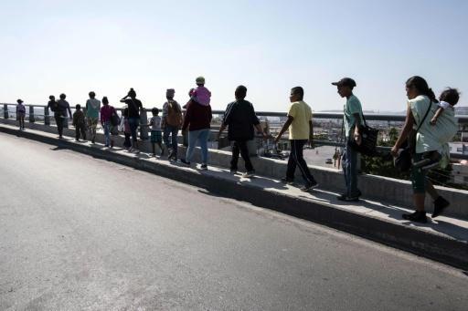 Migrantes cruzando el puente en Tijuana
