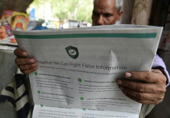 Un kiosquero de Nueva Deli lee un periódico con un anuncio de WhatsApp para luchar contra las noticias falsas