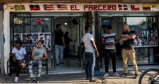 Migrantes haitianos permanecen en la puerta de un comercio en Santiago