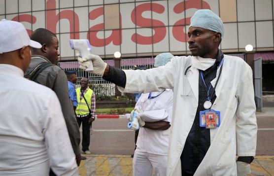  un trabajador de salud verifica la temperatura de las personas en el aeropuerto de Kinsasa, Congo,