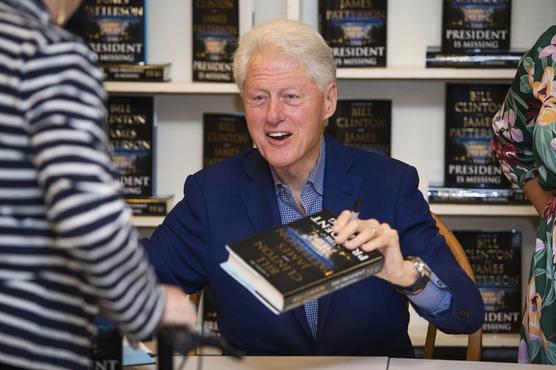 Bill Clinton sostiene un ejemplar de su libro