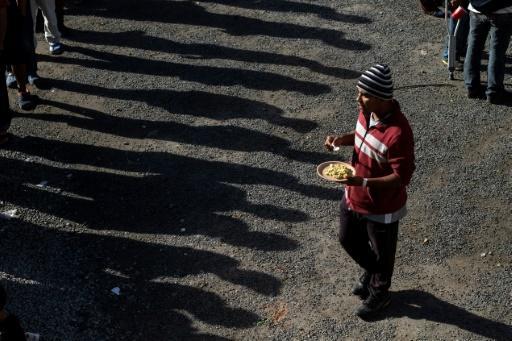Migrantes hacen fila para recibir comida en un nuevo albergue temporal en Tijuana