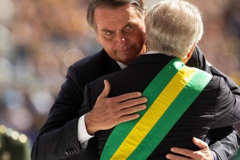 Jair Bolsonaro (de frente) estrecha en un abrazo a Michel Temer en la ceremonia de asunción. (foto: EPA)