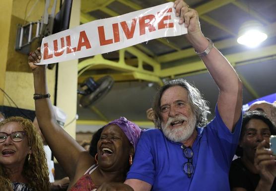 El actor brasileño Jose de Abreu, derecha, y una mujer sostienen un cartel con la leyenda "Lula Libre" 