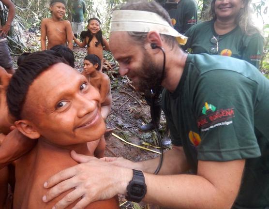  un indígena Korubo sonriendo a la cámara mientras un miembro de la FUNAI lo ausculta durante una expedición al Valle Javari