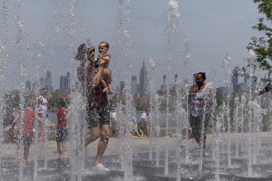 La gente disfruta el día en una fuente desde donde se ve el edificio Empire State en Williamsburg, Brooklyn