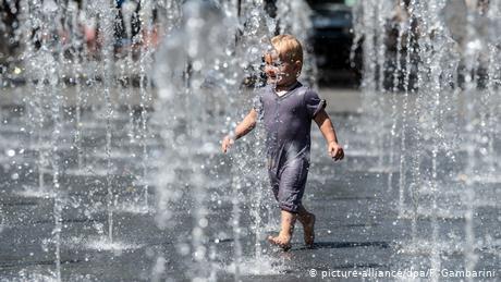 Un niño juega con el agua de una fuente en Alemania