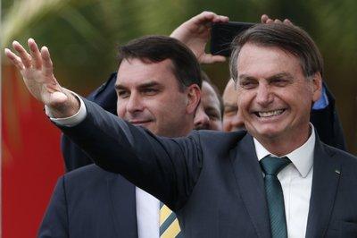 Acompañado por su hijo el senador Flavio Bolsonaro, el presidente brasileño Jair Bolsonaro saluda al lanzar nuevo partido