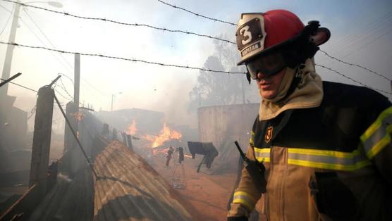 Bombero asiste a una vivienda incendiada en Valparaíso