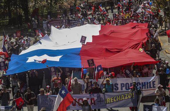 Manifestantes marchan con la bandera chilena durante una protesta contra la creación de una nueva Constitución