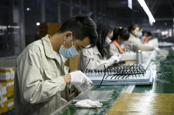 Unos trabajadores con mascarillas pule unas monturas de gafas en Wenzhou, China