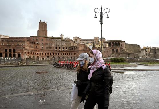 Dos mujeres con mascarillas protectoras pasan frente al Foro de Trajano, ayer en Roma