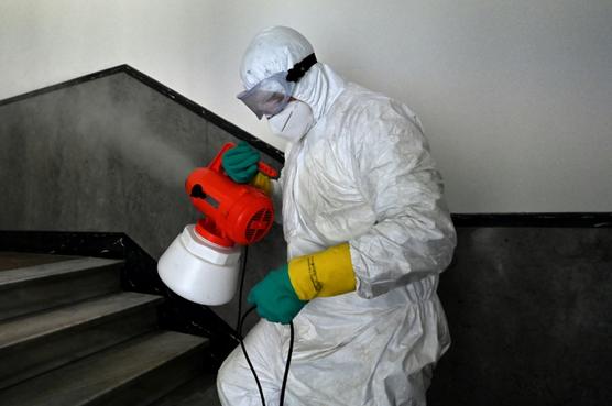 Un operario de una compañía privada rocía con desinfectante la escalera de un edificio de Roma, ayer