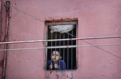 Un niño mira por la ventana de su casa en el barrio viejo de Nueva Delhi