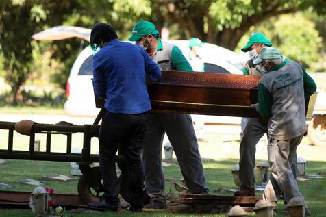 Empleados de un cementerio de San Pablo, Brasil, en plena tarea de sepultar fallecidos (foto: ANSA)