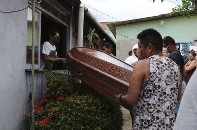 Familiares y empleados de una funeraria con trajes protectores trasladan un féretro en Manaos