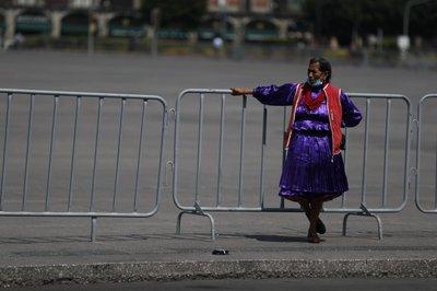 Una mujer indígena de pie junto al Zócalo de la Ciudad de México