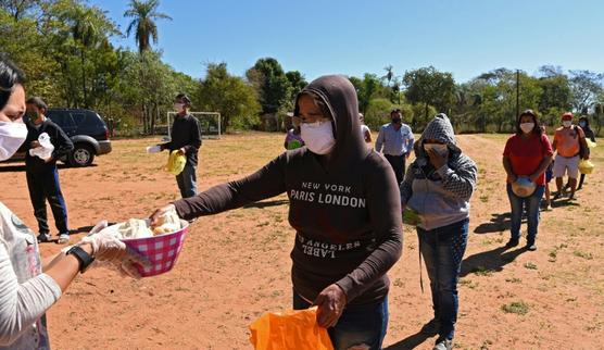 Vecinos con mascarillas hacen cola para recibir comida en Luque