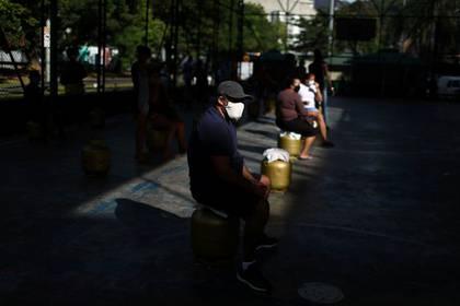 Vecinos con tapabocas esperan recibir garrafas de gas distribuidas por la Central Unica das Favelas (CUFA)