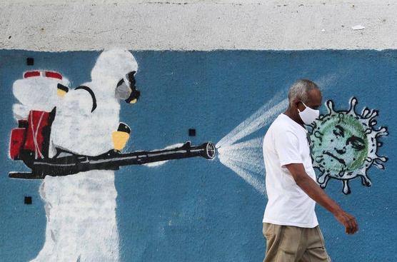 Un hombre camina junto a un graffiti que muestra a un limpiador 