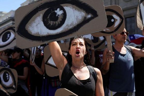 Una mujer sostiene una pancarta con un ojo pintado en apoyo a las victimas de la represión