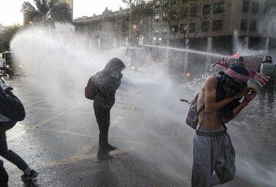 Manifestantes antigubernamentales son reprimidos con cañones de agua de la policía durante una protesta en Santiago