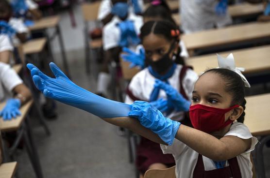 Una estudiante con máscara se pone guantes de plástico como medida de precaución