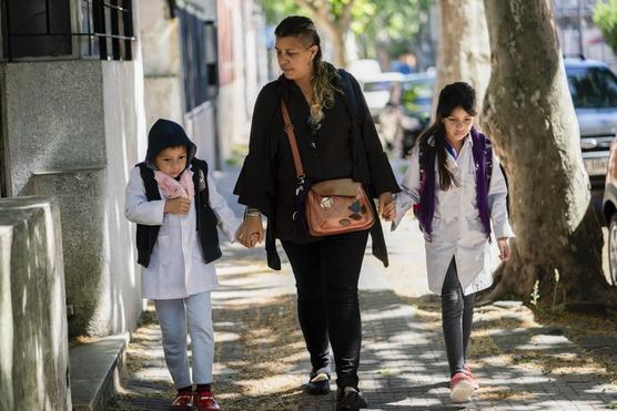 Madre lleva a sus hijos a la escuela en medio de la nueva pandemia de coronavirus en Montevideo, ayer