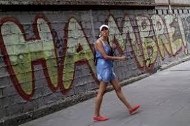 Mujer pasando frente a un mural con la frase "Hambre!"