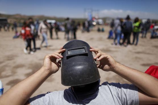 Usando una máscara de soldador como protección, un hombre ve un eclipse total en Piedra del Aguila, Argentina
