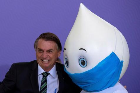 Jair Bolsonaro posa para las fotos con la mascota Ze Gotinha, creación para elevar la conciencia en el tema vacuna. (foto: ANSA)