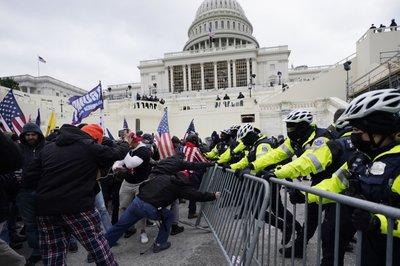 Partidarios del entonces presidente Donald Trump tratan de atravesar una barrera policial en el Capitolio en Washington