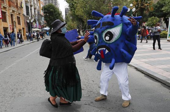Policía representa el virus COVID-19 intenta abrazar a un peatón, que se resiste, en el Paseo El Prado