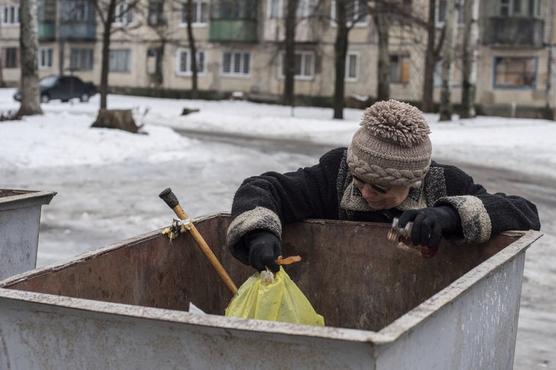 Una mujer busca comida en un contenedor de basura en Avdiivka, Ucrania