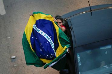 Una mujer sostiene una bandera brasileña durante una caravana para protestar contra el cierre del gobernador de Brasilia