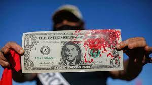Manifestante agita un dolar con el rostro de Bolsonaro y ensangrentado