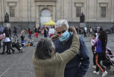 Una señora le coloca el tapaboca a su marido en el centro de Santiago