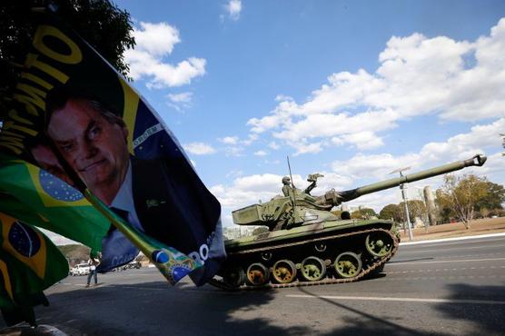 Bandera con rostro de Bolsonaro saluda paso de tanque 