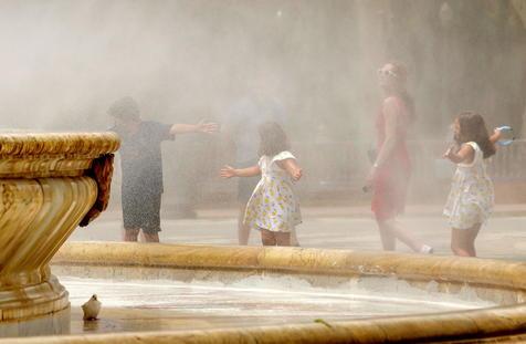 Turistas se refrescan en una fuente de la Plaza de España, en Sevilla. (foto: EPA)