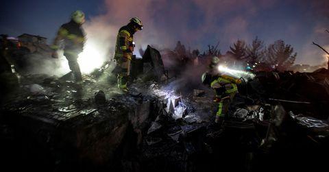 Los bomberos trabajan en medio de restos de casas que fueron quemadas luego de la propagación de un incendio forestal 