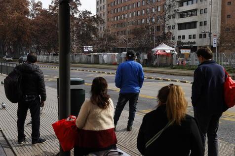 Un grupo de personas espera el autobús para ir a trabajar, en Santiago (foto: ANSA)