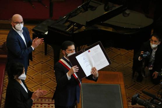 Boric sostiene la versión final de la nueva constitución del país durante una ceremonia en el antiguo Congreso