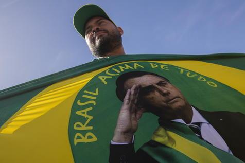 Un seguidor de Jair Bolsonaro y una imagen elocuente del presidente de Brasil (foto: ANSA)