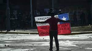 Un manifestante sostiene una bandera de Chile durante enfrentamientos con la policía 