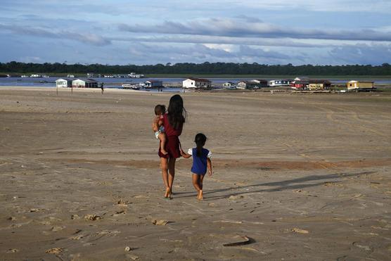 Tres niños caminan en una zona afectada por la sequía cerca del río Solimões
