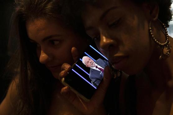 Dos mujeres escuchan en un teléfono un discurso de Luiz Inácio Lula da Silva