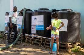 Un trabajador de la compañía estatal de agua rellena unos bidones instalados por el ministerio de Salud Pública dominicano