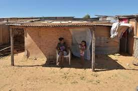 Una mujer y su hija descansan afuera de su casa en un asentamiento levantado tras una inundación en Asunción